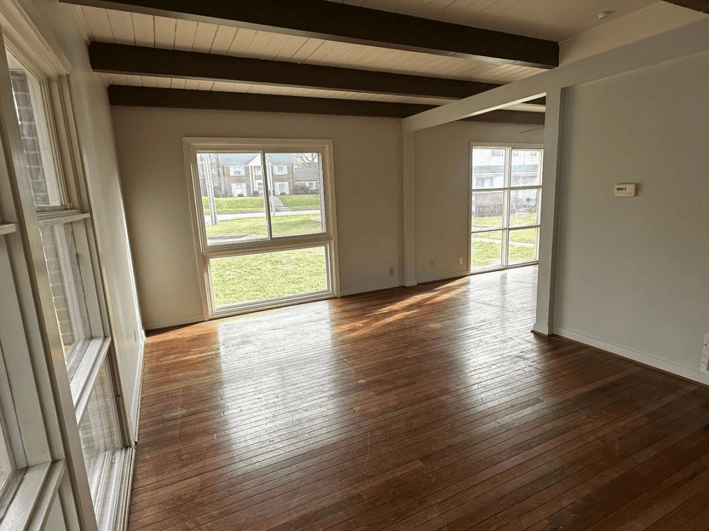 Empty living room in a vacant house with hardwood floors and natural light